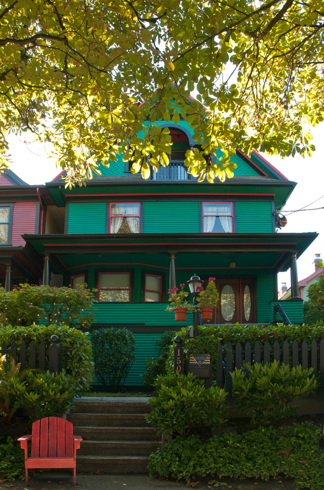 На фото: трехэтажный, зеленый, большой, деревянный частный загородный дом в викторианском стиле с двускатной крышей и крышей из гибкой черепицы с