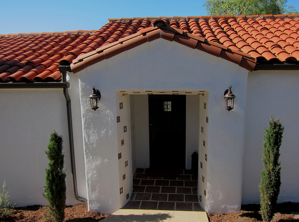 Inspiration for a mid-sized mediterranean white one-story stucco house exterior remodel in Santa Barbara with a clipped gable roof and a tile roof