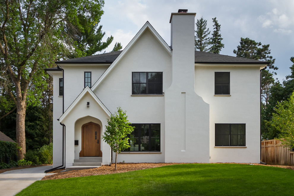 Imagen de fachada de casa blanca tradicional renovada de dos plantas con revestimiento de estuco y tejado de teja de madera