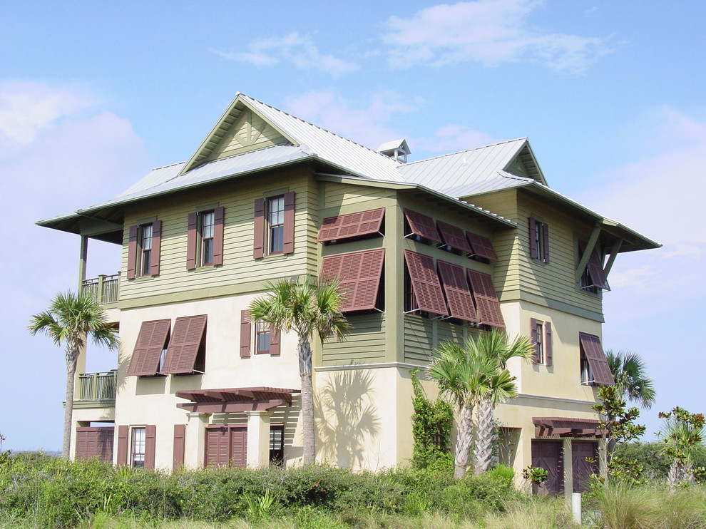 Esempio della facciata di una casa grande verde tropicale a tre piani con rivestimenti misti e tetto a capanna