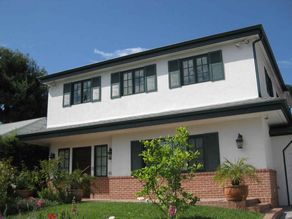 Idée de décoration pour une façade de maison beige vintage en stuc de taille moyenne et à un étage avec un toit à quatre pans.