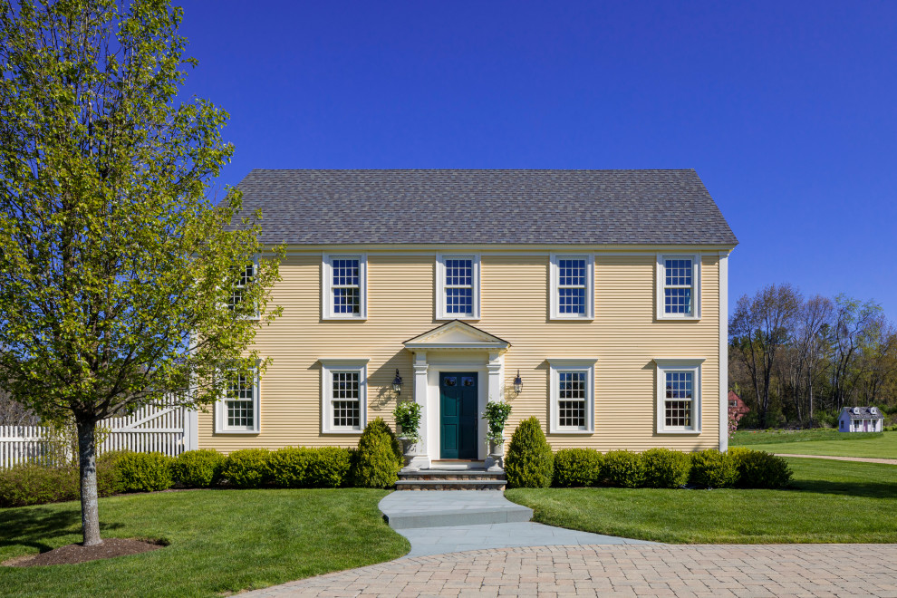 Zweistöckiges Klassisches Einfamilienhaus mit gelber Fassadenfarbe, Satteldach, Schindeldach, grauem Dach und Verschalung in Boston