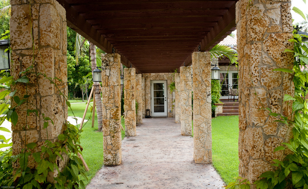 Immagine della facciata di una casa ampia tropicale a due piani con rivestimento in pietra