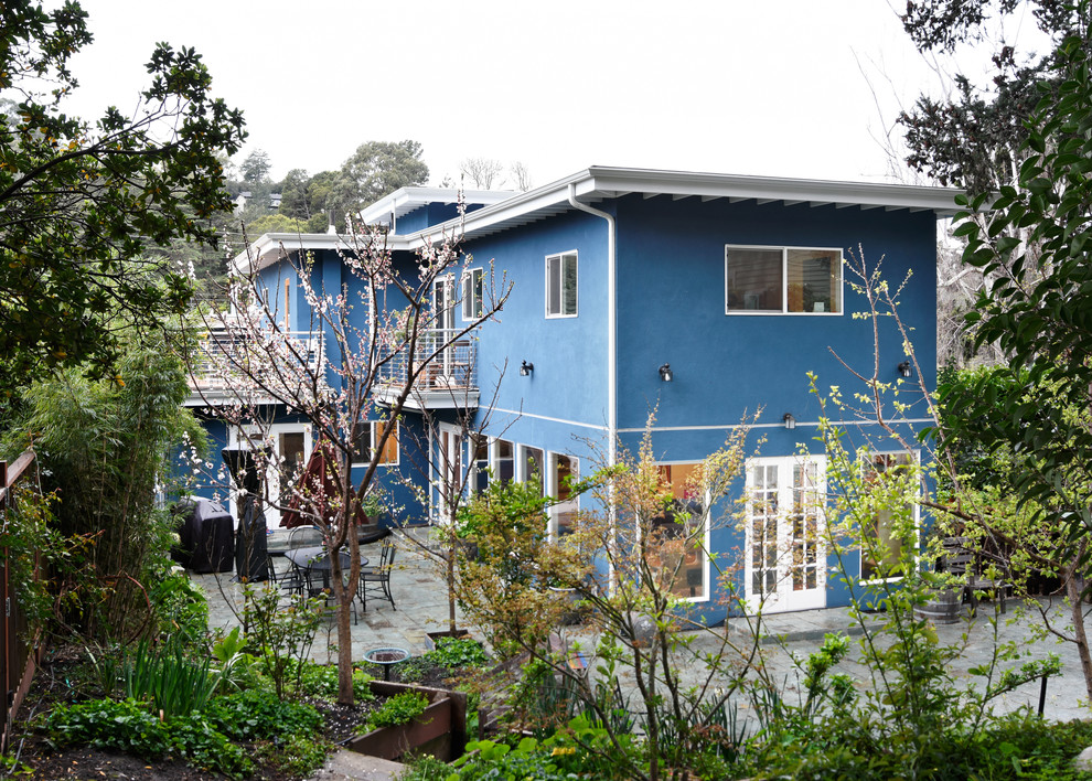 Imagen de fachada de casa azul contemporánea de tamaño medio de dos plantas con revestimiento de estuco y tejado plano