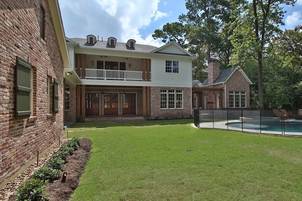 Mid-sized elegant red two-story brick exterior home photo in Houston with a hip roof