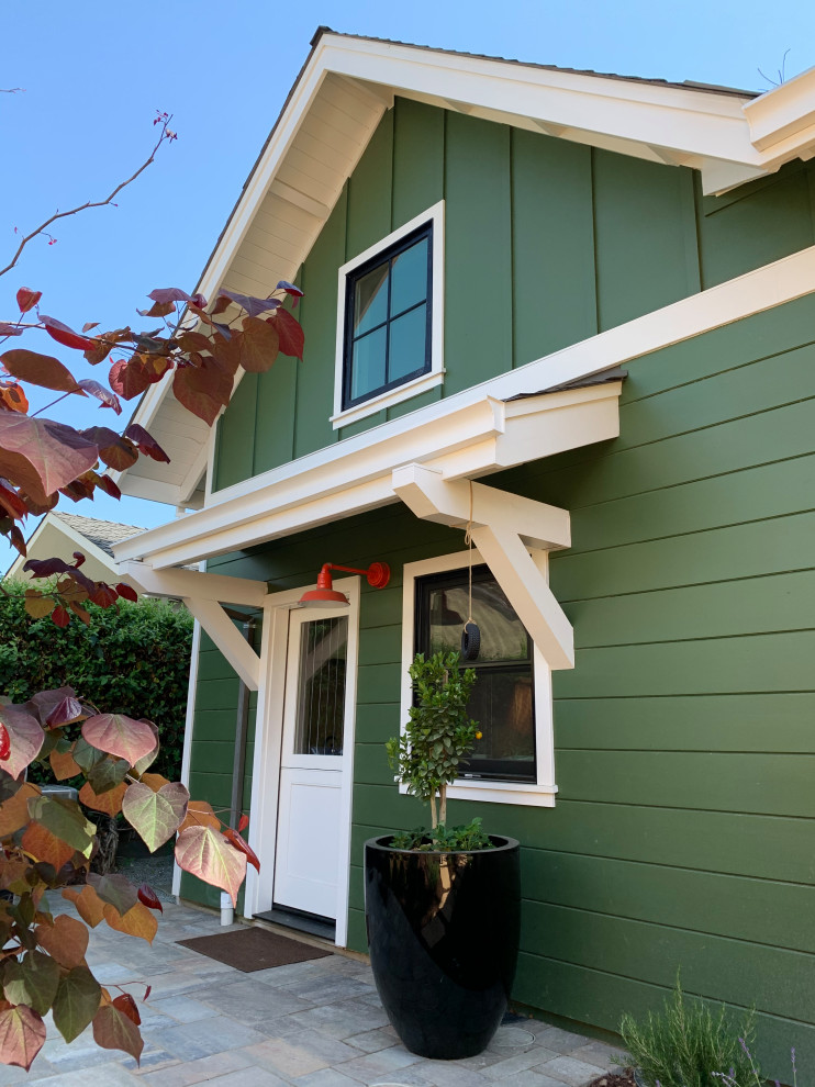Immagine della villa piccola verde american style a due piani con rivestimento in legno, tetto a capanna, copertura a scandole, tetto grigio e pannelli sovrapposti