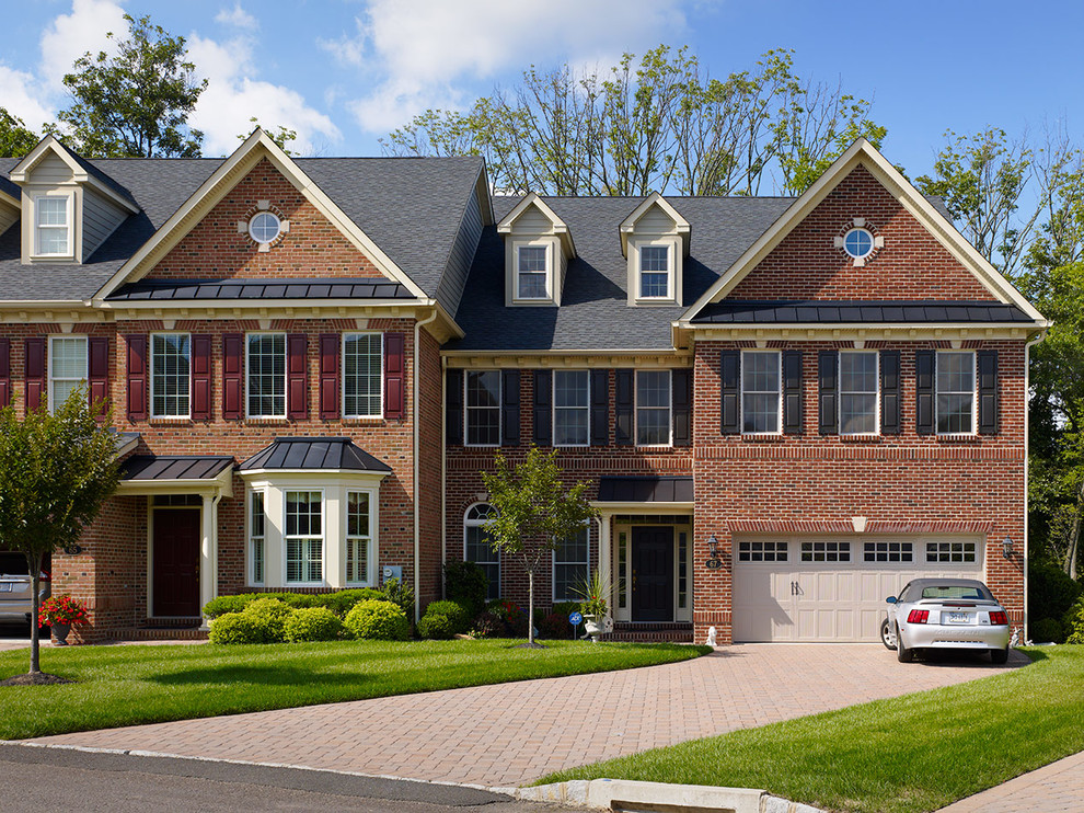 Cette image montre une grande façade de maison rouge design en brique à un étage avec un toit à deux pans.
