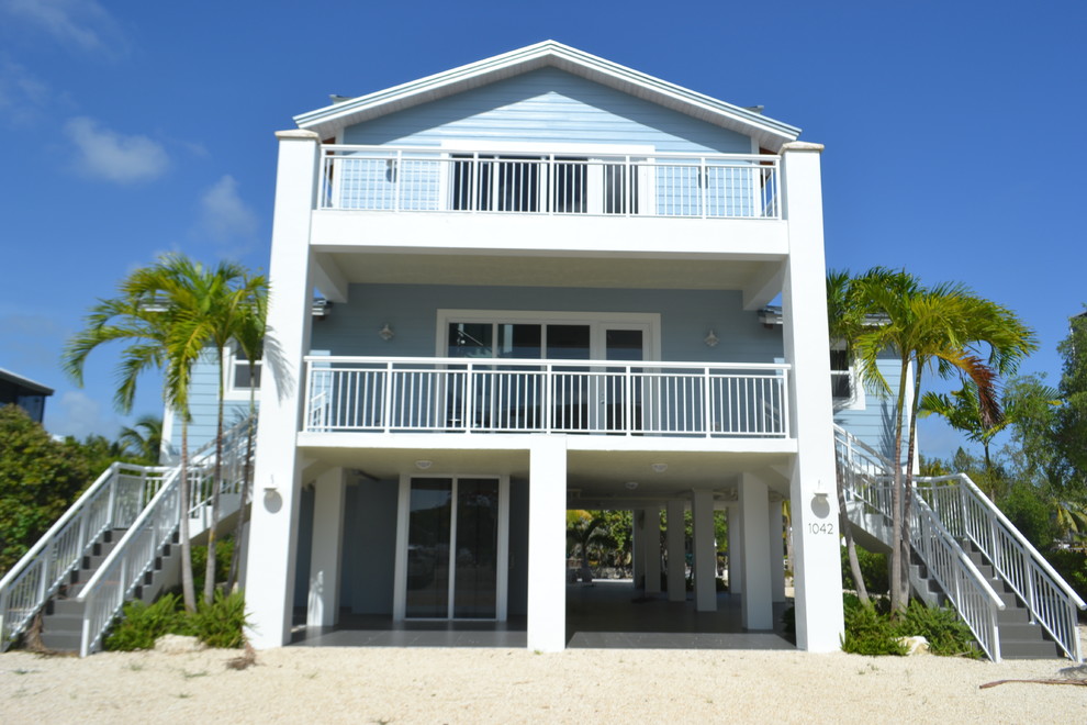 Foto de fachada de casa azul tropical grande de tres plantas con revestimiento de vinilo y tejado a dos aguas