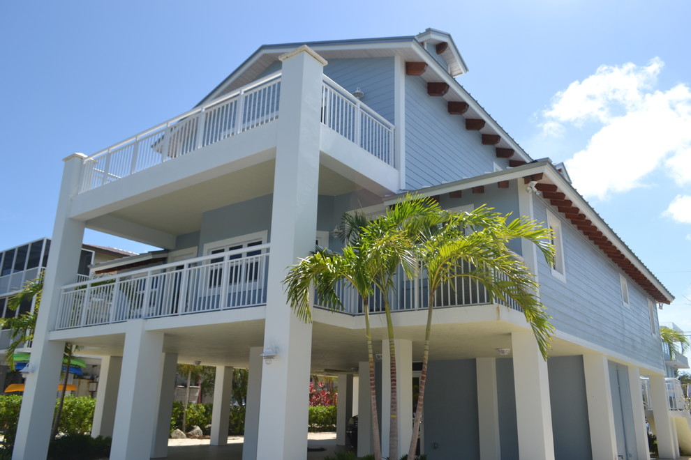 Foto della villa grande blu tropicale a tre piani con rivestimento in vinile e tetto a capanna