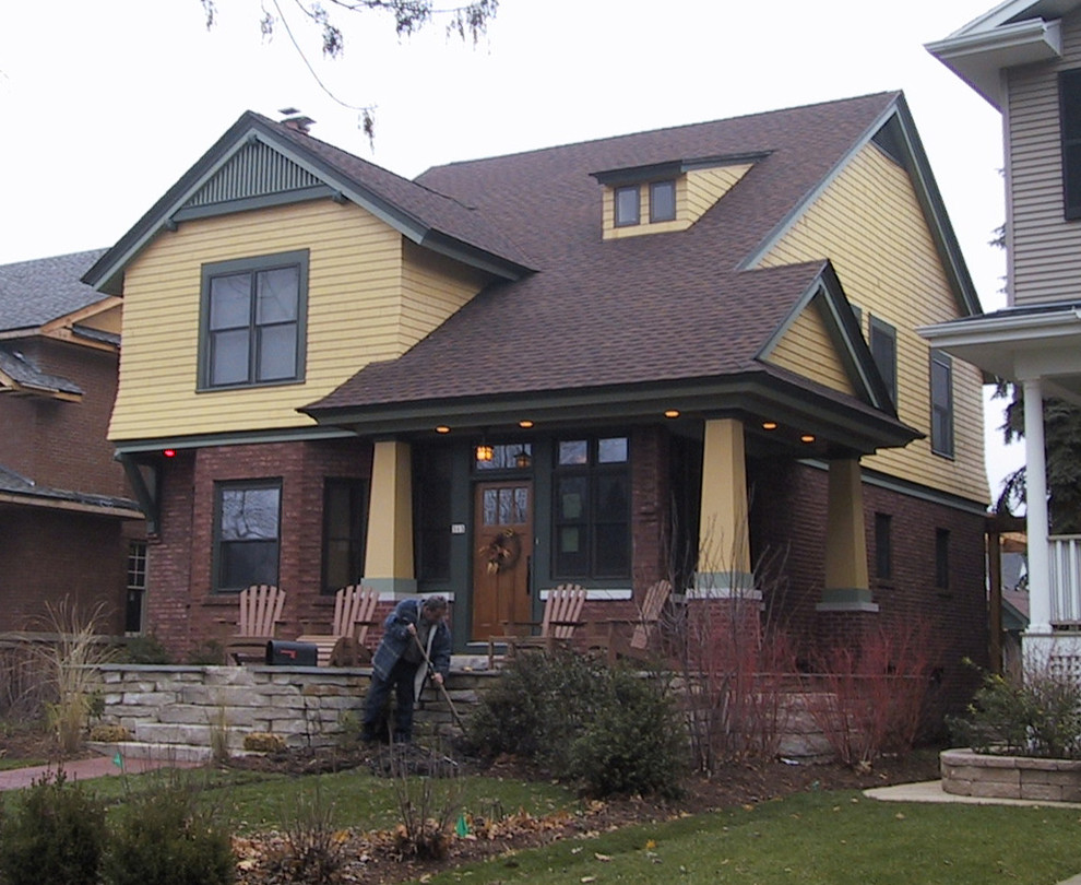 Réalisation d'une grande façade de maison jaune craftsman à un étage avec un toit à deux pans et un revêtement mixte.