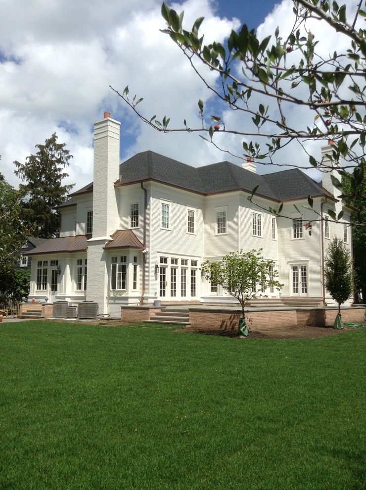 Diseño de fachada de casa blanca clásica grande con revestimiento de ladrillo y tejado a cuatro aguas