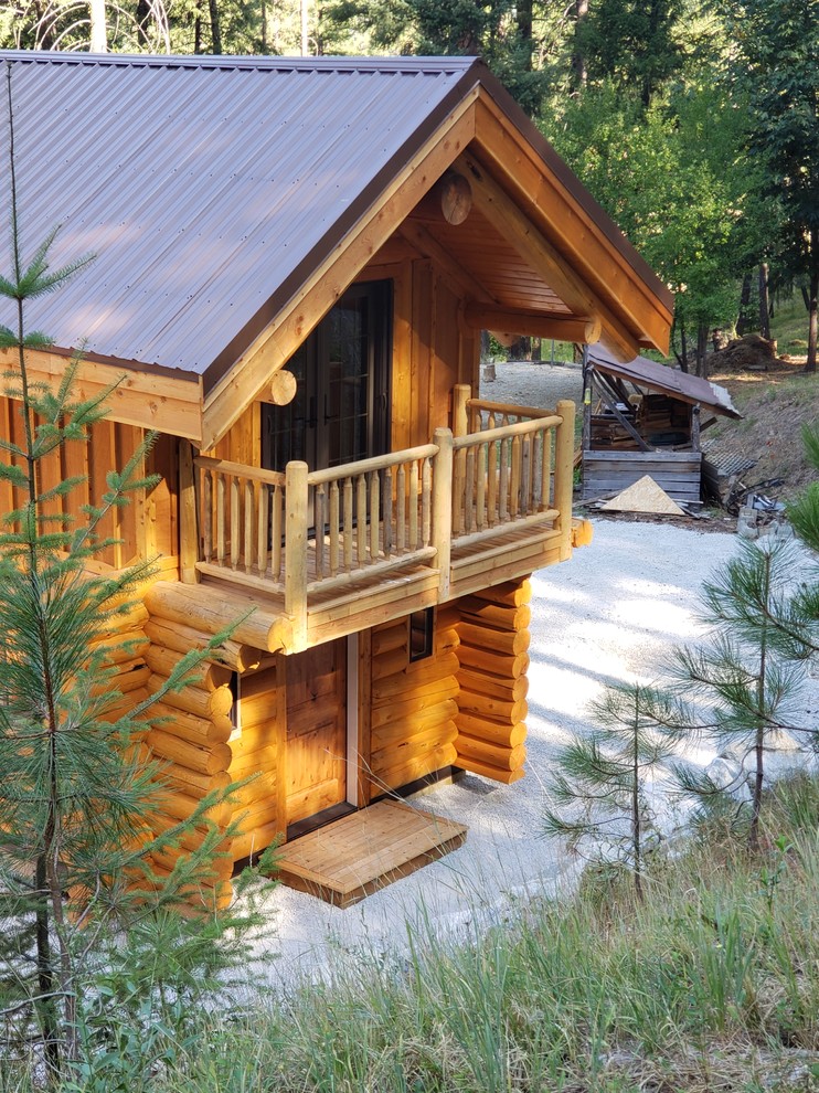 Cette photo montre une façade de maison marron montagne en bois de taille moyenne et à un étage avec un toit à deux pans et un toit en métal.