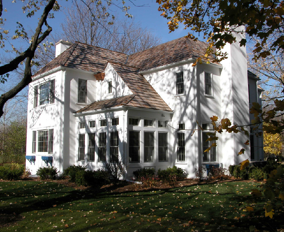 Modelo de fachada blanca clásica grande de dos plantas con revestimiento de estuco y tejado a cuatro aguas