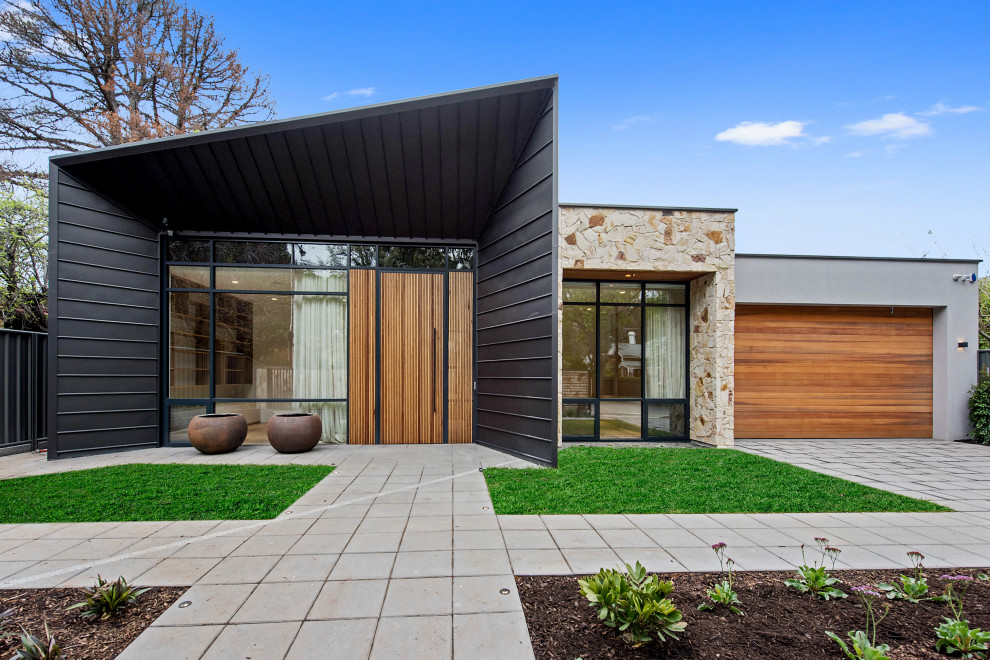 Diseño de fachada de casa multicolor actual grande de una planta con revestimientos combinados y tejado plano