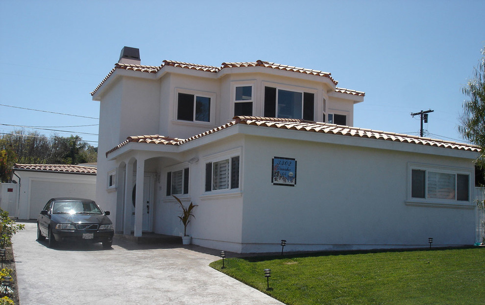 Пример оригинального дизайна: двухэтажный, белый частный загородный дом среднего размера в средиземноморском стиле с облицовкой из цементной штукатурки, вальмовой крышей и черепичной крышей