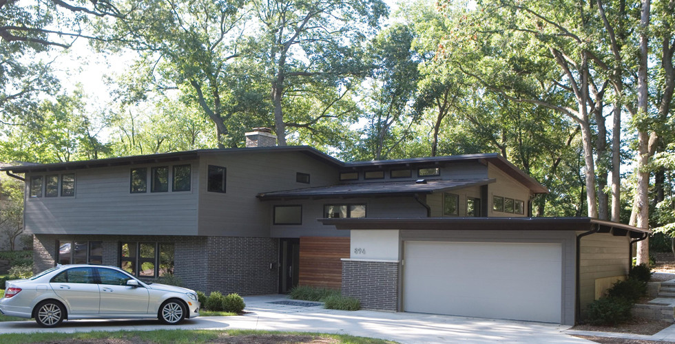 Cette image montre une grande façade de maison grise vintage à un étage avec un revêtement mixte et un toit plat.
