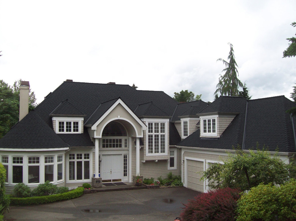 Immagine della villa grande beige classica a due piani con tetto a padiglione e copertura a scandole