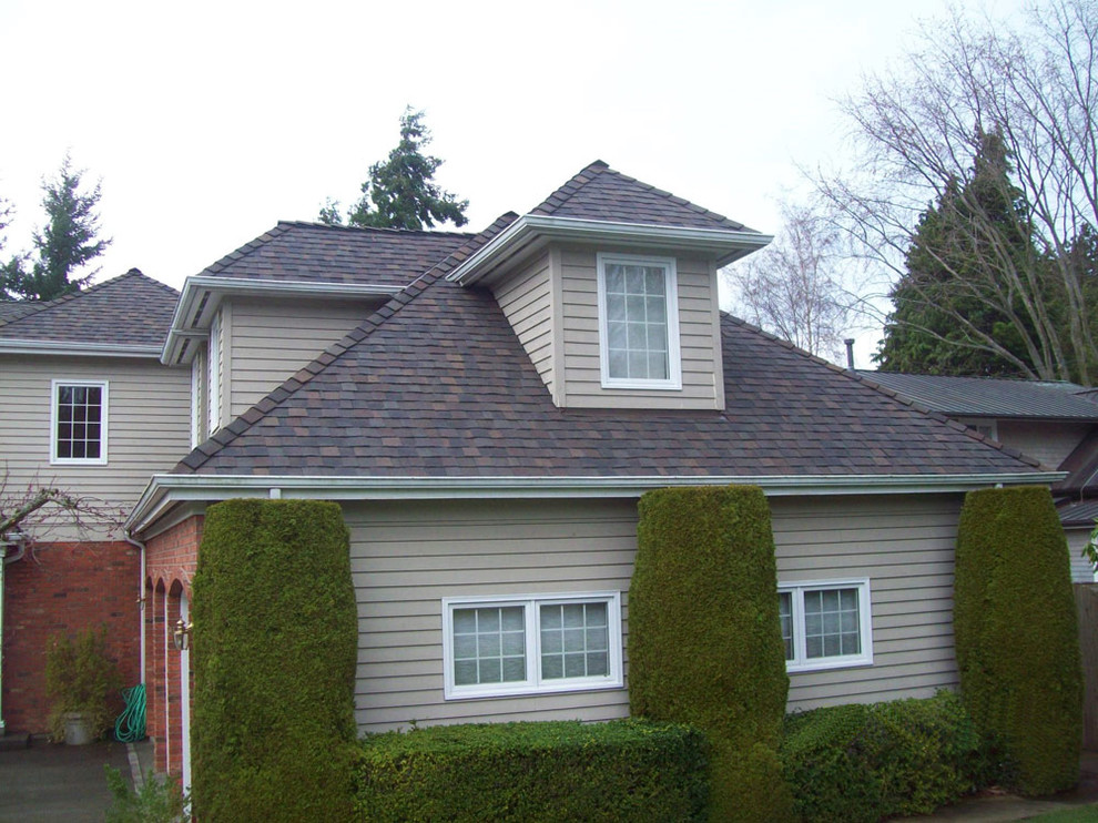 Modelo de fachada de casa beige tradicional grande de dos plantas con tejado a cuatro aguas y tejado de teja de madera