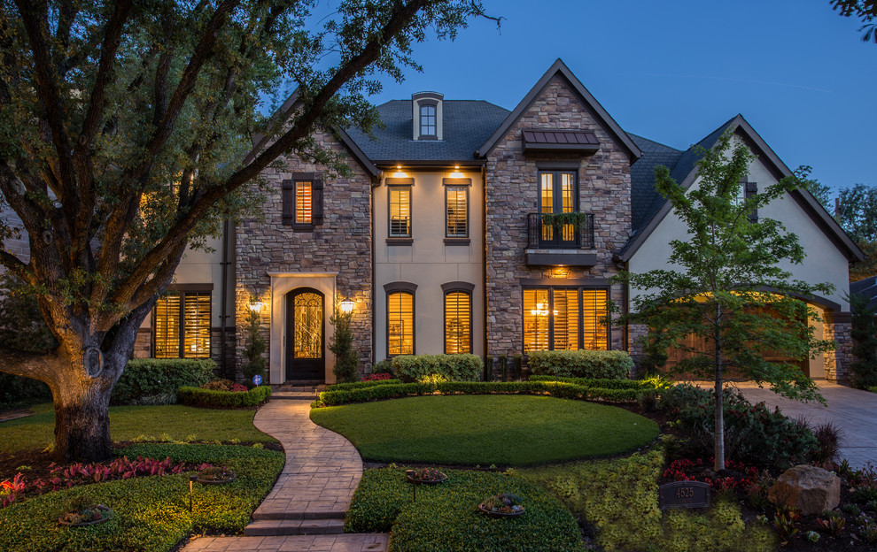 Large classic two floor house exterior in Houston with stone cladding and a hip roof.