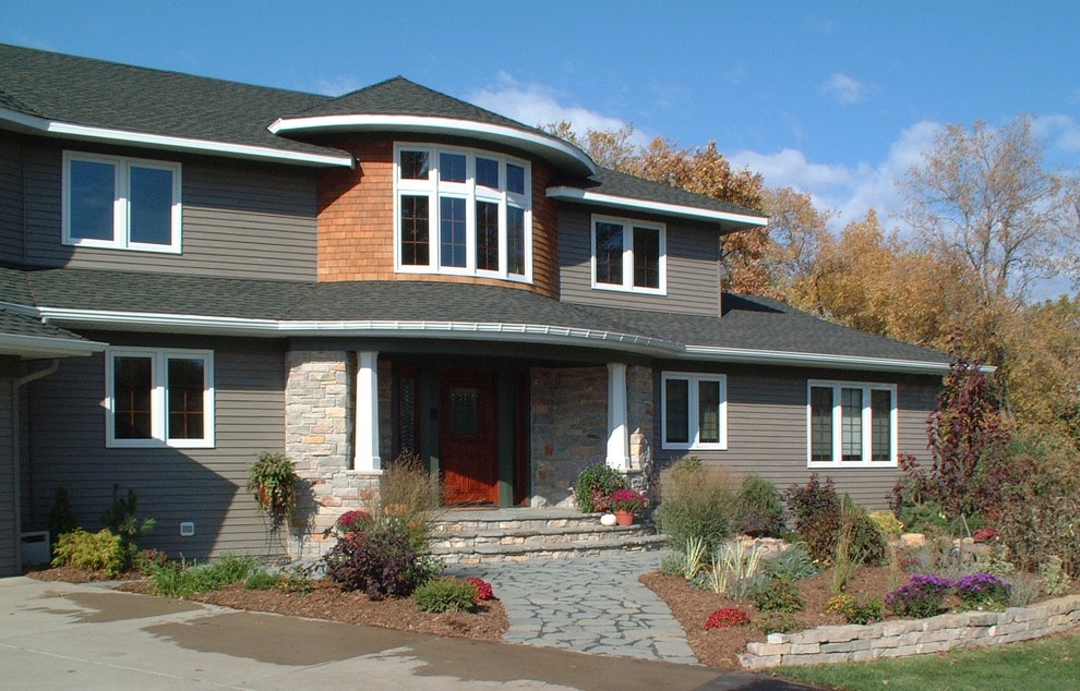 Imagen de fachada de casa gris de estilo americano grande de dos plantas con revestimiento de aglomerado de cemento, tejado a cuatro aguas y tejado de teja de madera