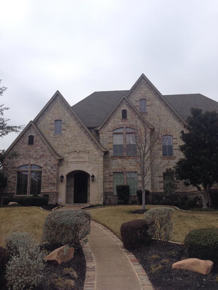 This is an example of an expansive and beige traditional house exterior in Dallas with three floors, stone cladding and a hip roof.