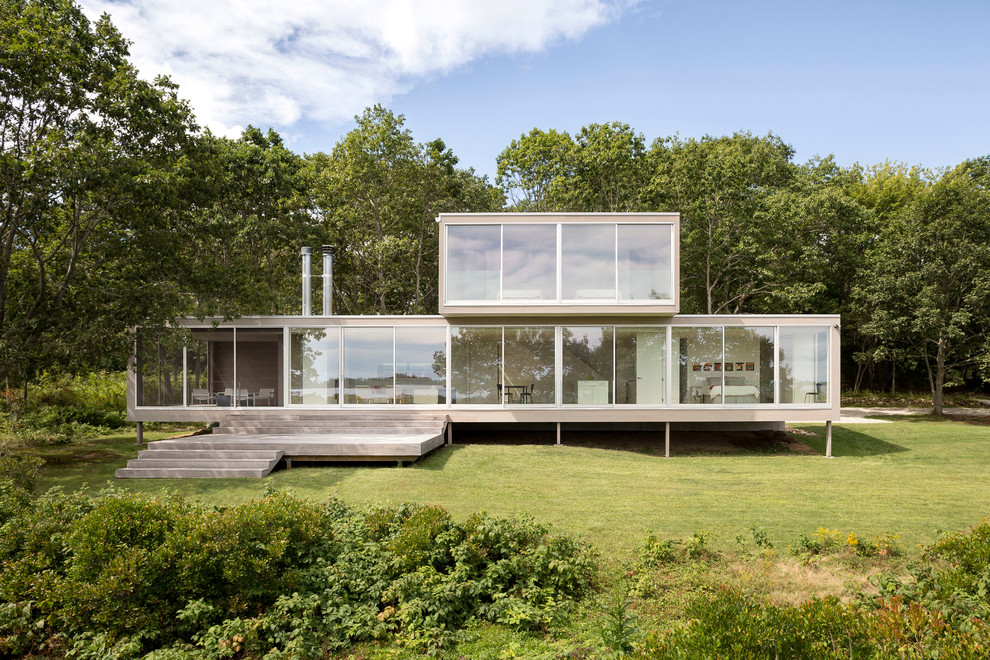 Idée de décoration pour une façade de maison minimaliste en verre à un étage avec un toit plat.