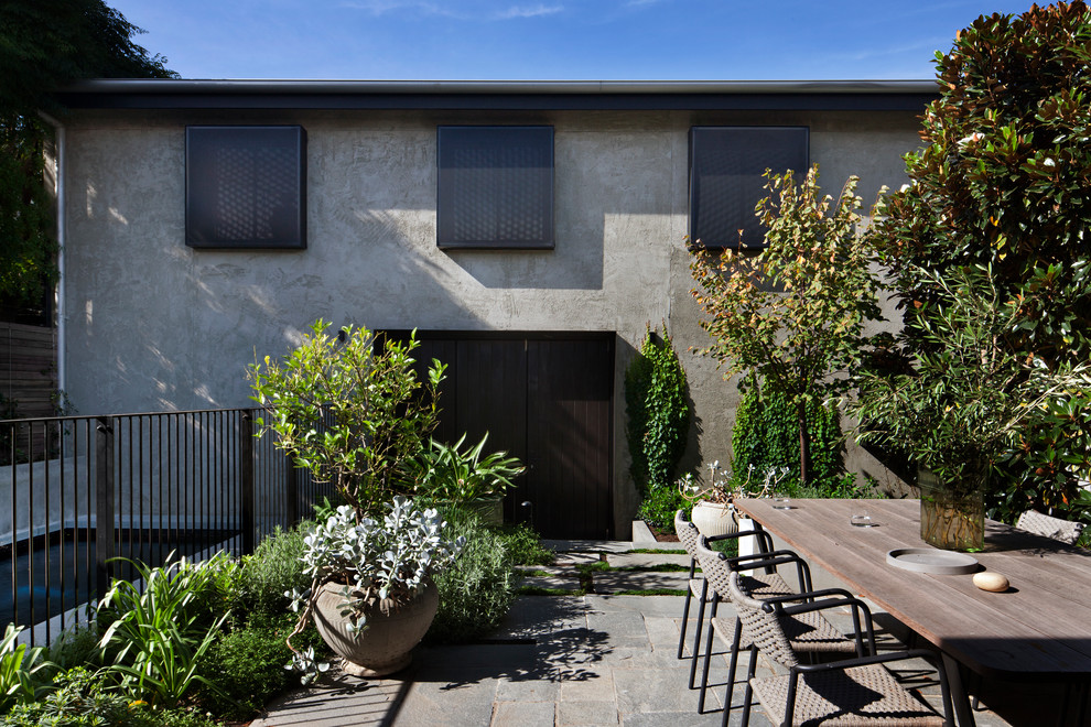 Foto de fachada de casa gris actual de tamaño medio de dos plantas con revestimiento de estuco, tejado plano y tejado de metal