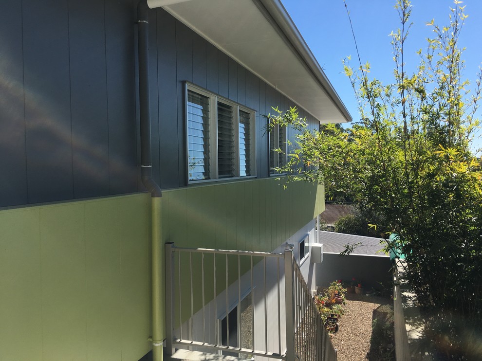 Cette photo montre une façade de maison verte tendance de taille moyenne et à un étage avec un revêtement mixte, un toit plat et un toit en métal.
