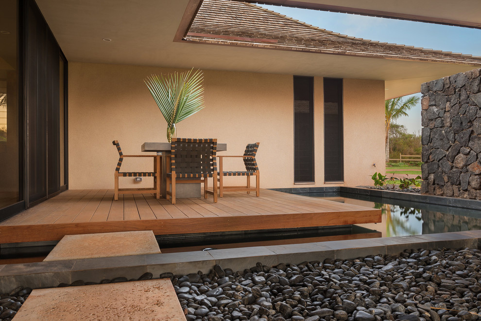 Ejemplo de fachada de casa beige tropical con tejado a cuatro aguas