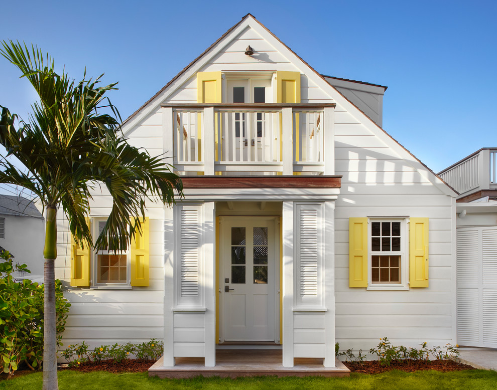 Immagine della facciata di una casa bianca stile marinaro a due piani con rivestimento in legno e tetto a capanna