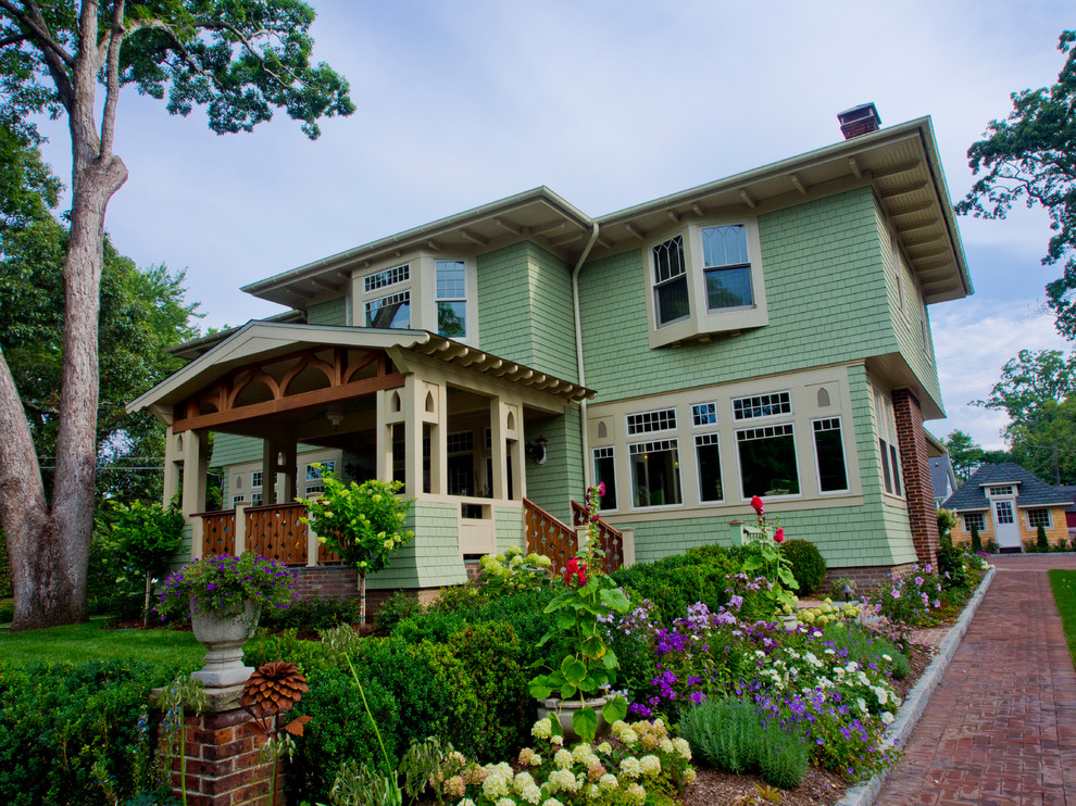 Exemple d'une façade de maison verte craftsman en bois de taille moyenne et à un étage avec un toit à quatre pans.