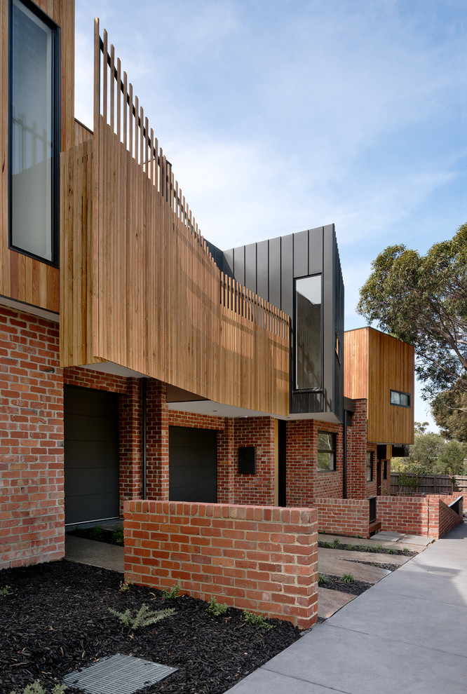 Medium sized and red contemporary two floor brick house exterior in Melbourne with a flat roof.