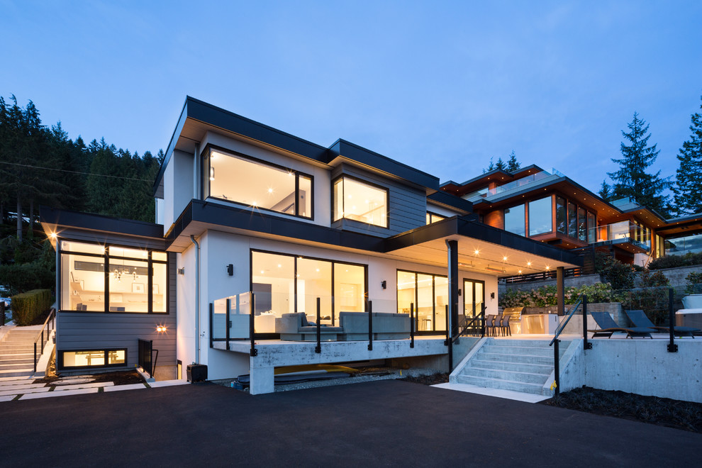 Réalisation d'une grande façade de maison multicolore design à un étage avec un revêtement mixte, un toit plat et un toit végétal.