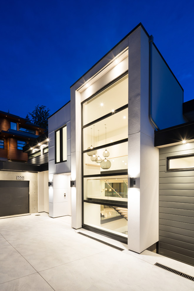 Diseño de fachada de casa gris contemporánea grande de tres plantas con revestimiento de metal, tejado plano y techo verde