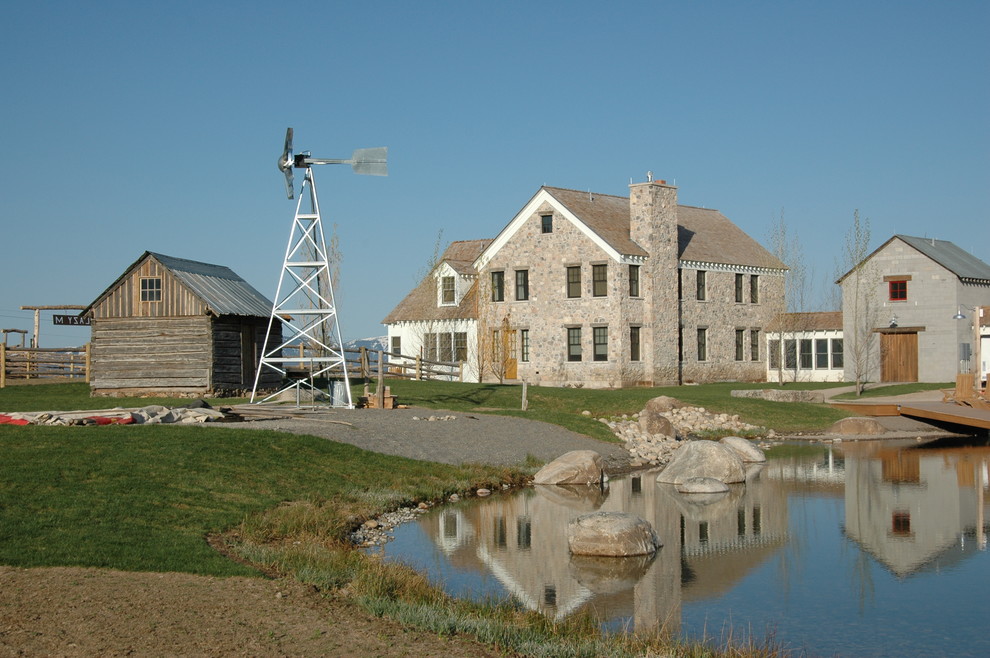 Cette photo montre une grande façade de maison nature en pierre à deux étages et plus avec un toit à deux pans.