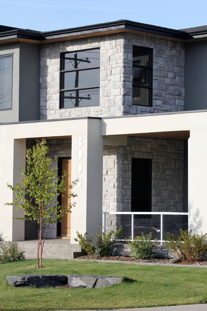 Example of a mid-sized trendy gray two-story stucco exterior home design in Calgary