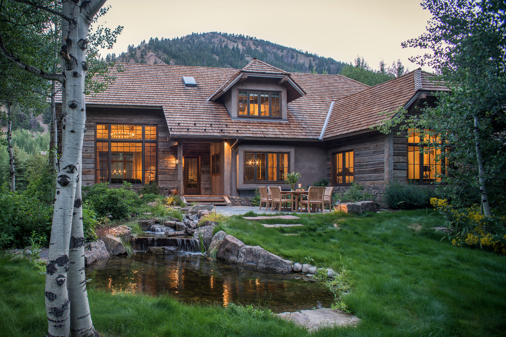 Inspiration for a brown rustic house exterior in Other with wood cladding and a half-hip roof.