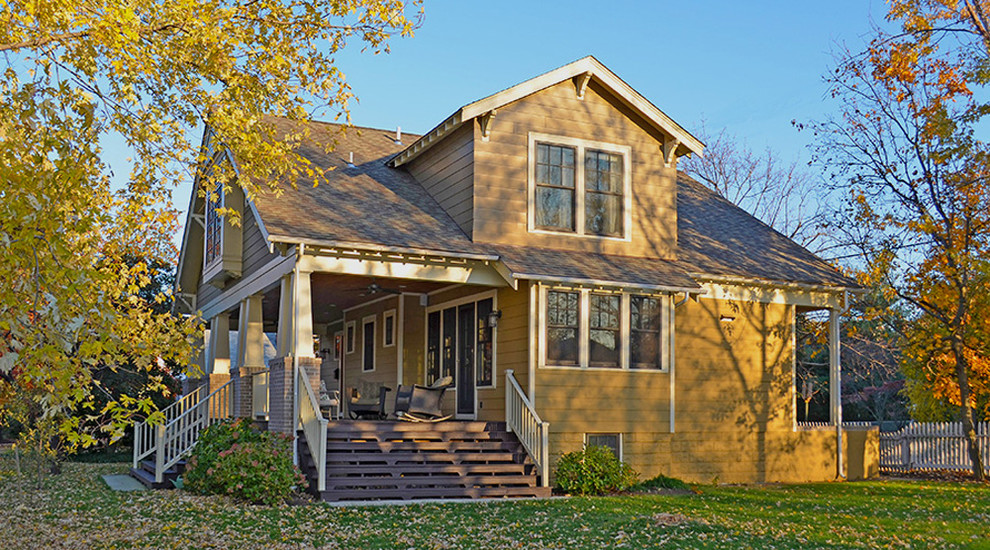Aménagement d'une façade de maison jaune classique en bois de taille moyenne et à un étage avec un toit à deux pans.