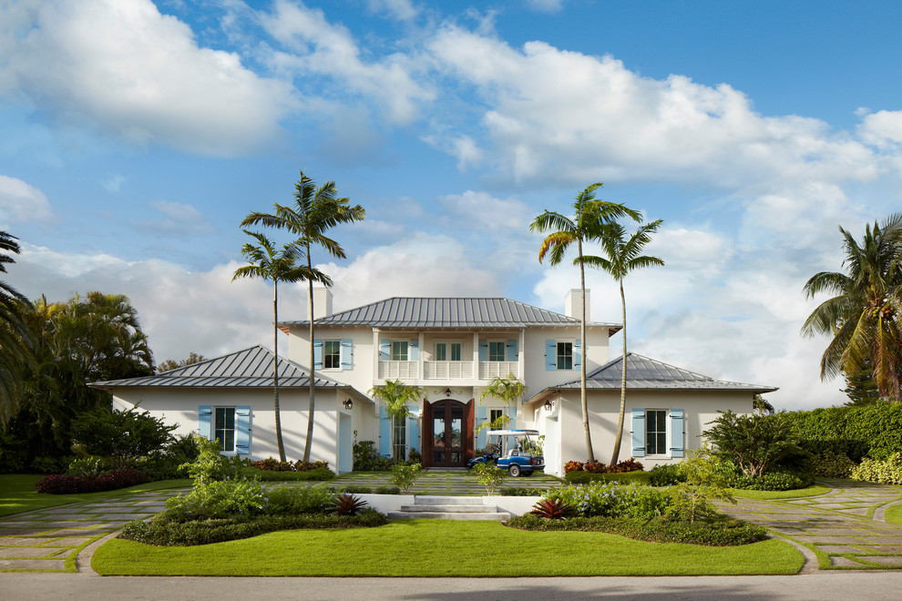 Example of a large island style white two-story stucco exterior home design in Miami with a hip roof