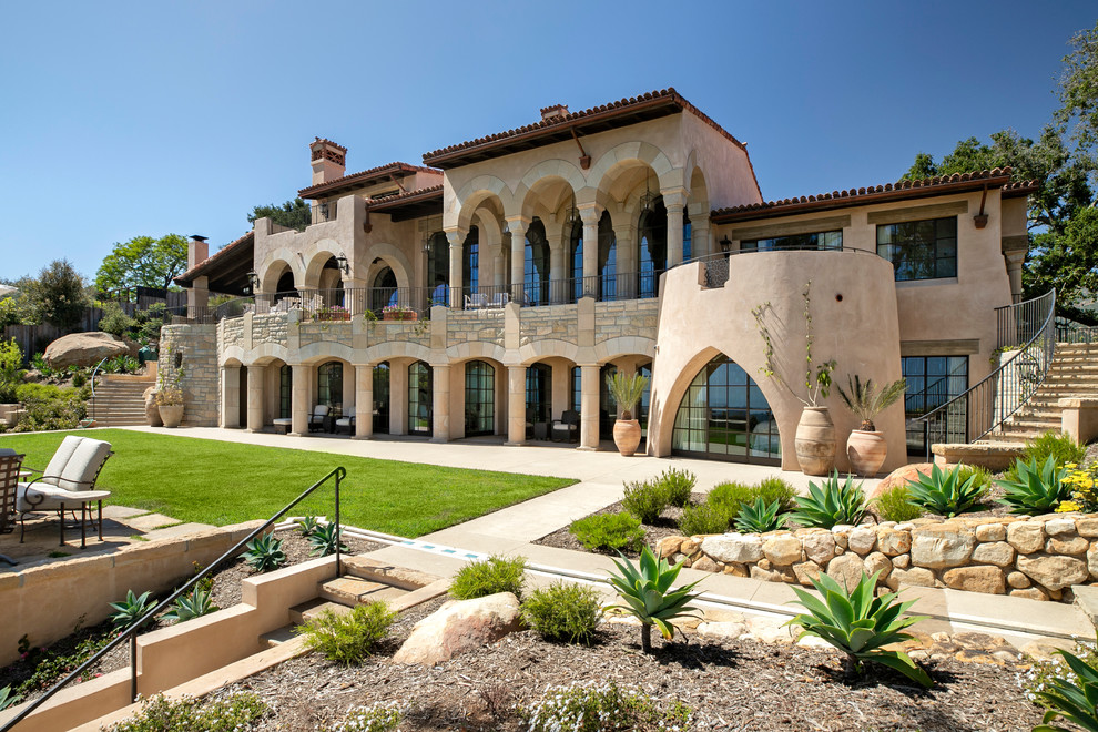 Inspiration for a large mediterranean beige three-story house exterior remodel in Santa Barbara with a shed roof and a tile roof