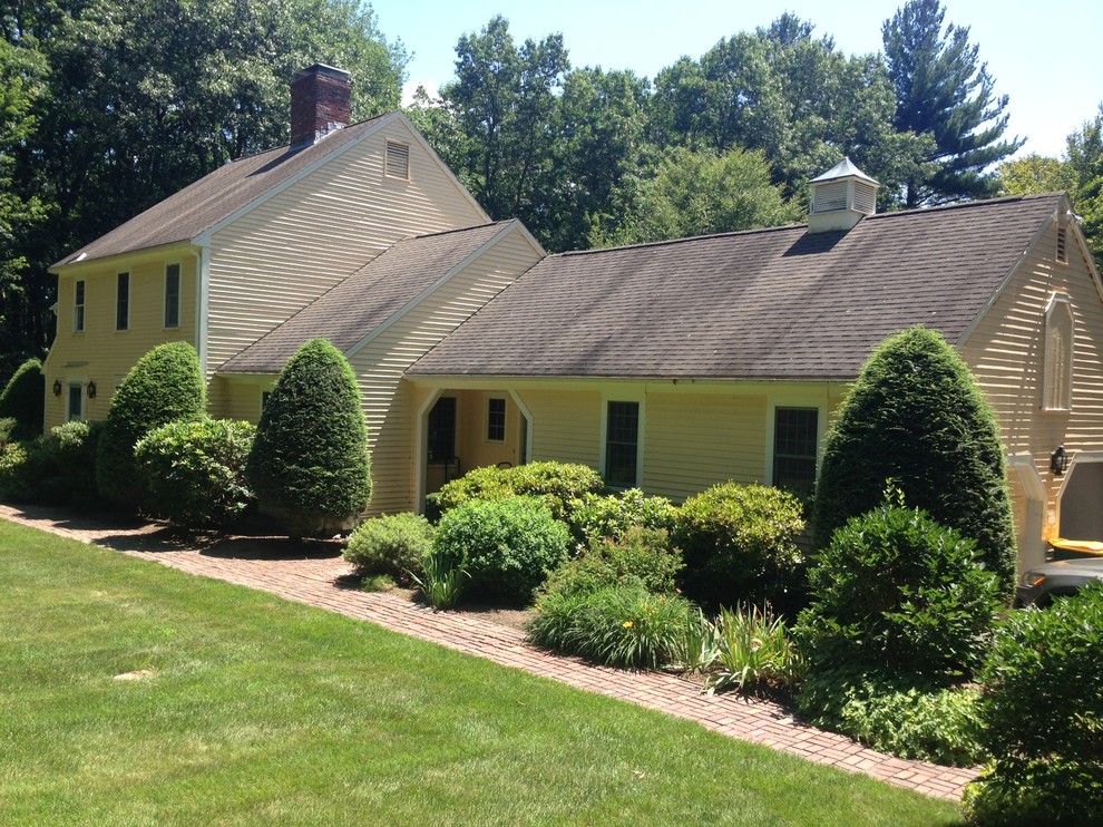 Imagen de fachada de casa amarilla clásica renovada grande de dos plantas con revestimiento de vinilo, tejado a dos aguas y tejado de teja de barro