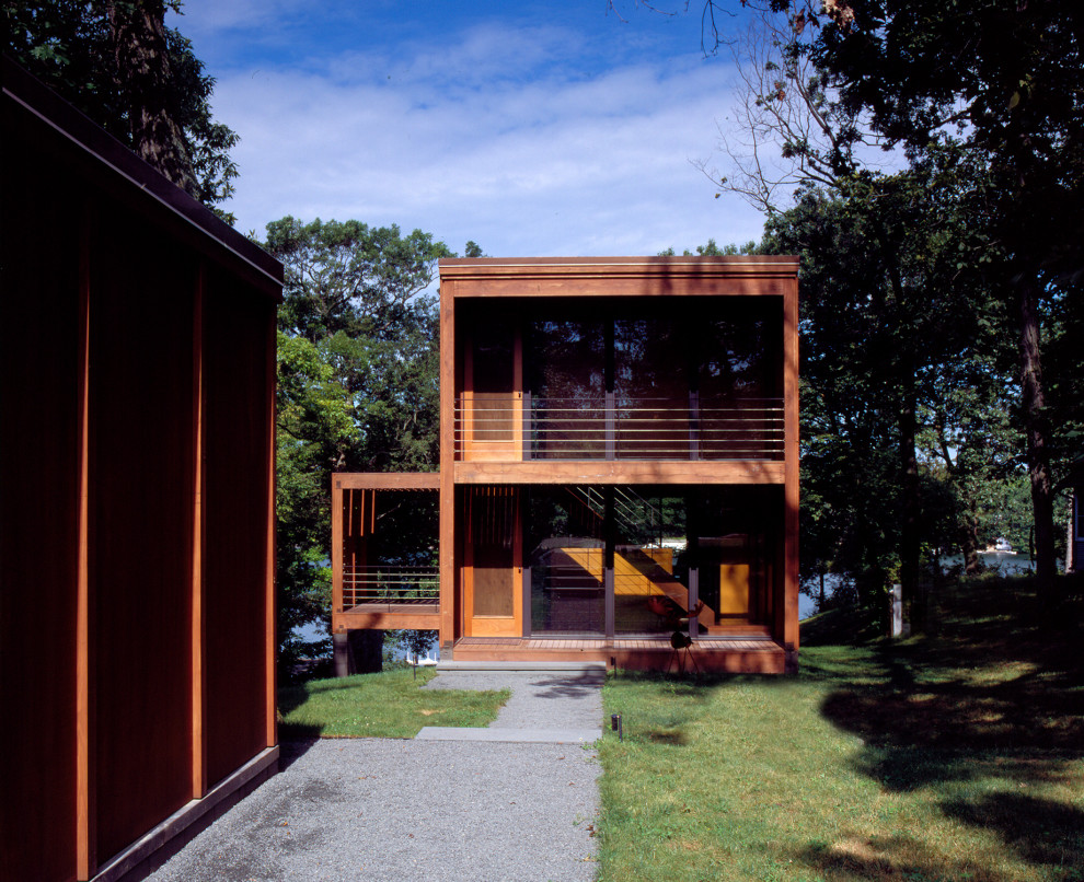 Exemple d'une façade de maison marron moderne en bois de taille moyenne et à deux étages et plus avec un toit plat et un toit en métal.