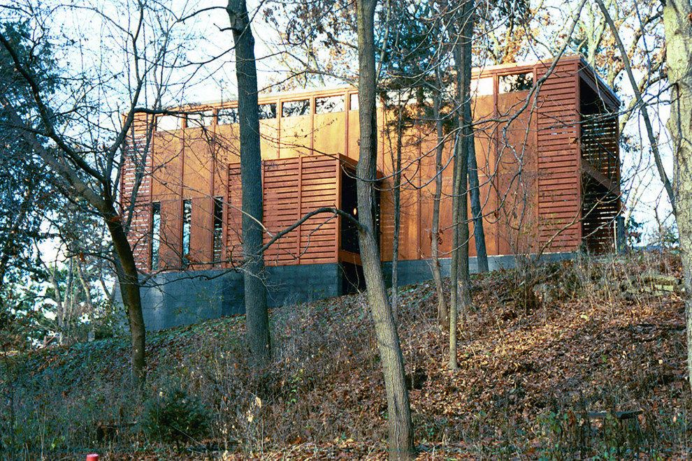На фото: деревянный, коричневый, маленький, трехэтажный частный загородный дом в стиле модернизм с плоской крышей и металлической крышей для на участке и в саду
