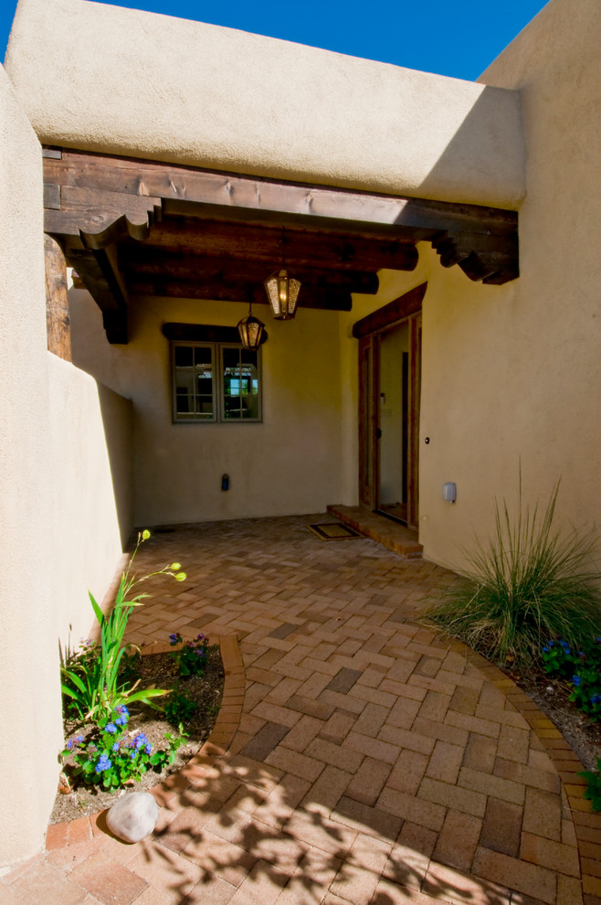 Cette image montre une façade de maison marron sud-ouest américain en adobe de taille moyenne et de plain-pied avec un toit plat.