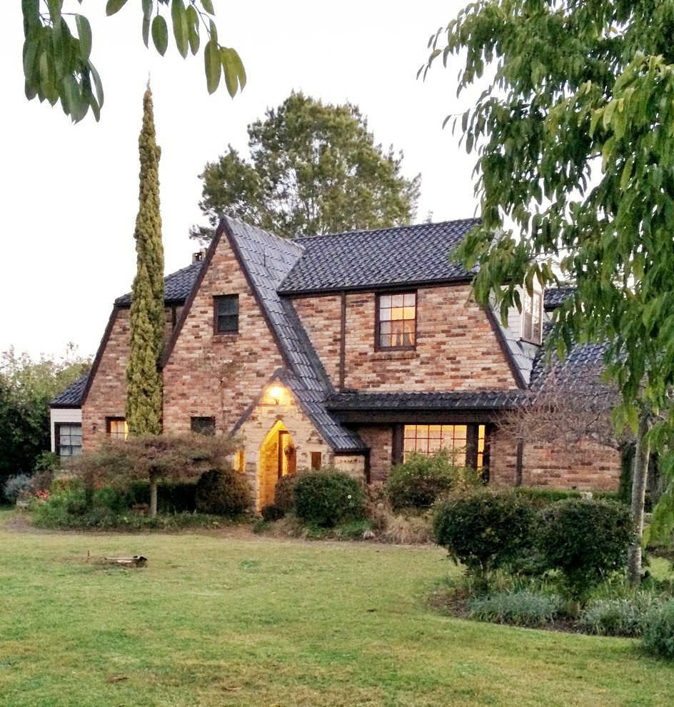 Imagen de fachada de casa marrón de estilo de casa de campo grande de dos plantas con revestimiento de ladrillo, tejado a dos aguas y tejado de teja de barro