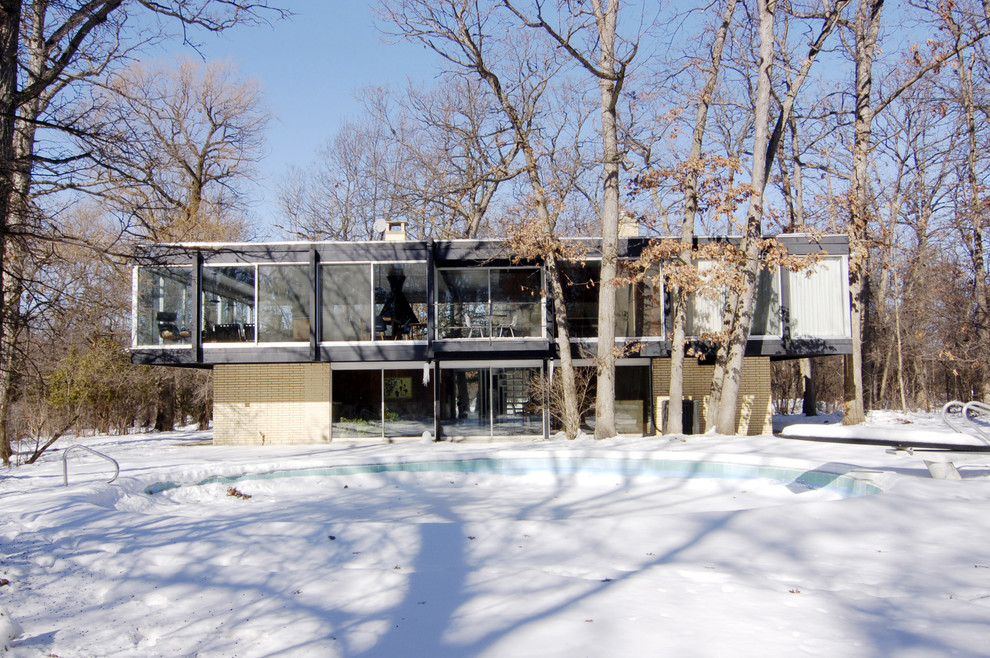 Photo of a medium sized modern two floor glass house exterior in Other.