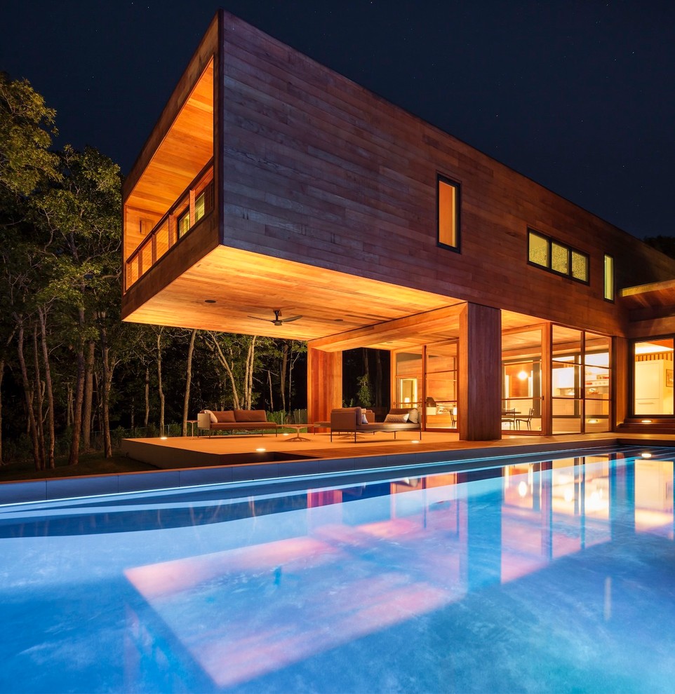На фото: двухэтажный, деревянный, коричневый дом в современном стиле с плоской крышей с