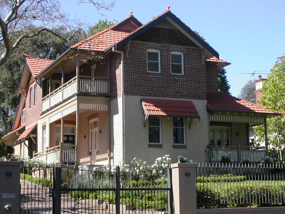 Imagen de fachada roja clásica de dos plantas con revestimiento de ladrillo y tejado a dos aguas
