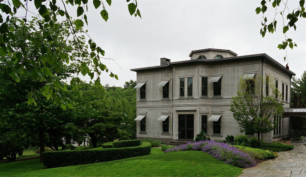 Inspiration pour une grande façade de maison grise traditionnelle en bois à un étage avec un toit à quatre pans.