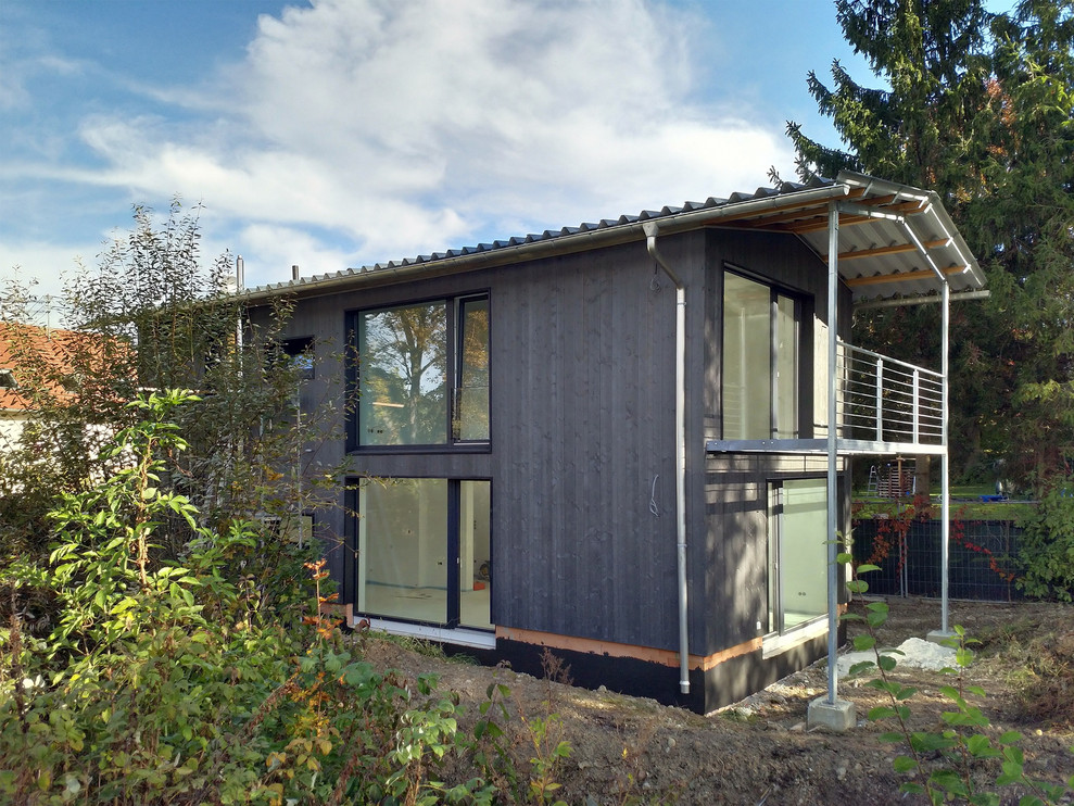 Idee per la villa nera country a due piani di medie dimensioni con rivestimento in legno, tetto a capanna e copertura in metallo o lamiera